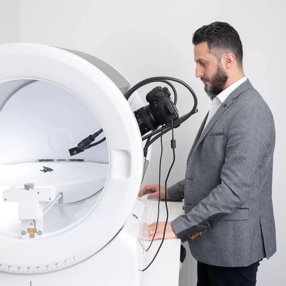 Uomo in abito mentre utilizza un dispositivo fotografico Orbitvu