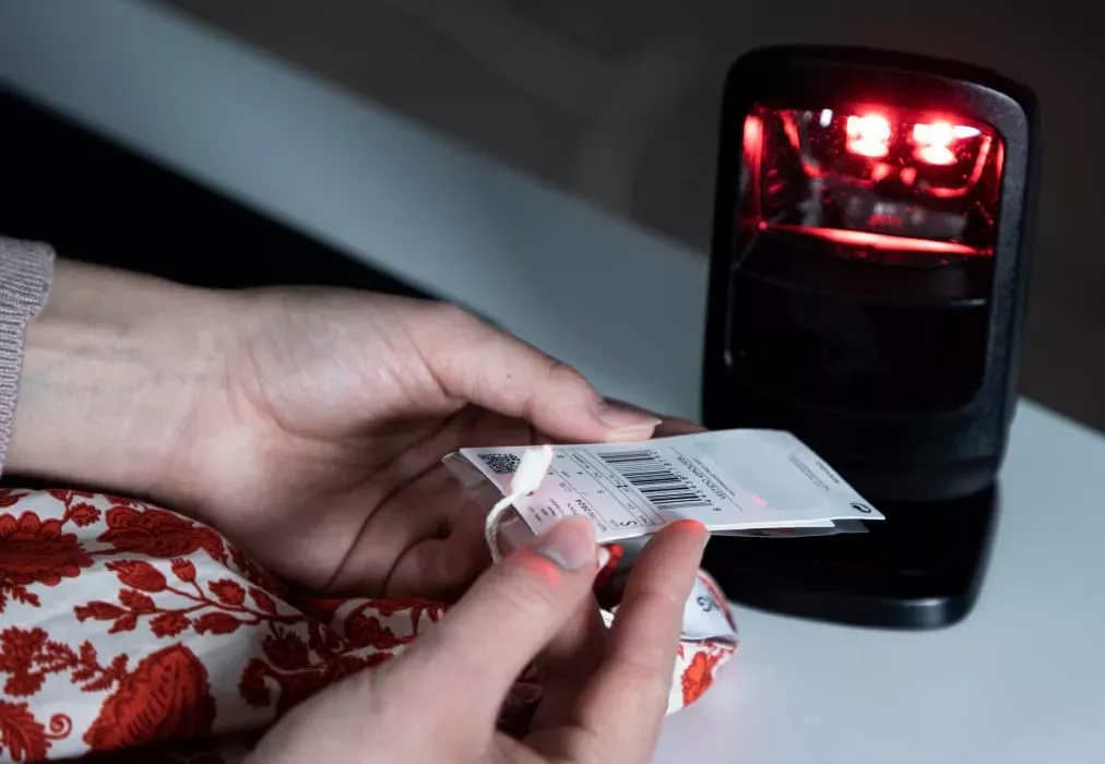 Primo piano di mani che scansionano il codice a barre di un capo d'abbigliamento per l'inventario