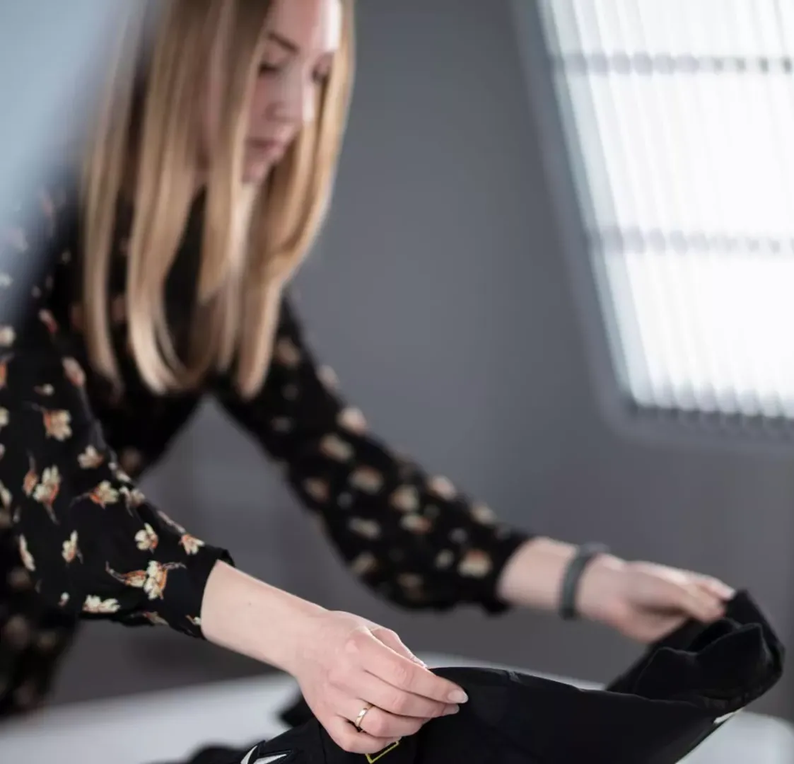 Product stylist che dispone un capo d'abbigliamento nero per uno shooting flat lay