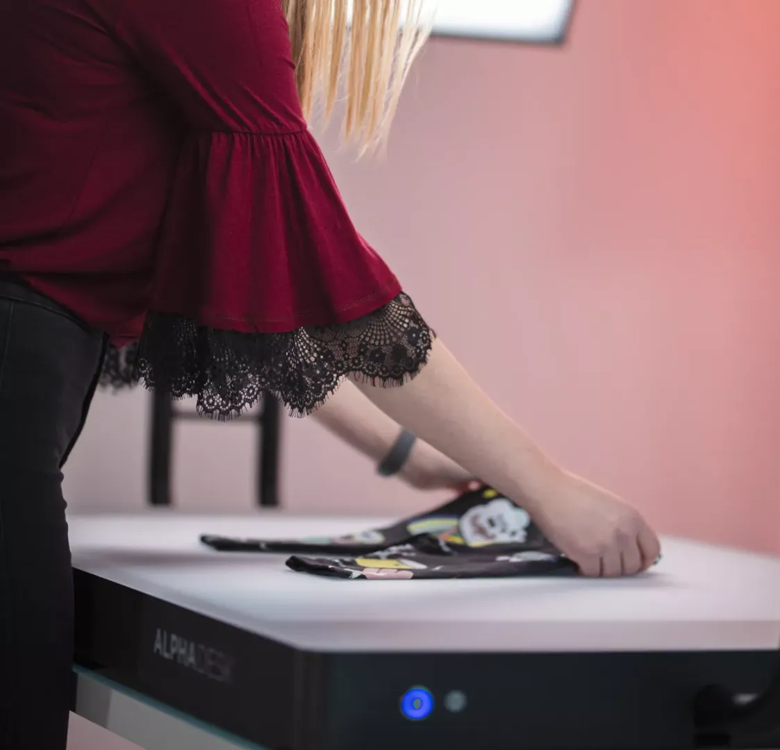 Donna che piega abiti per bambini su una scrivania bianca con Alphadesk